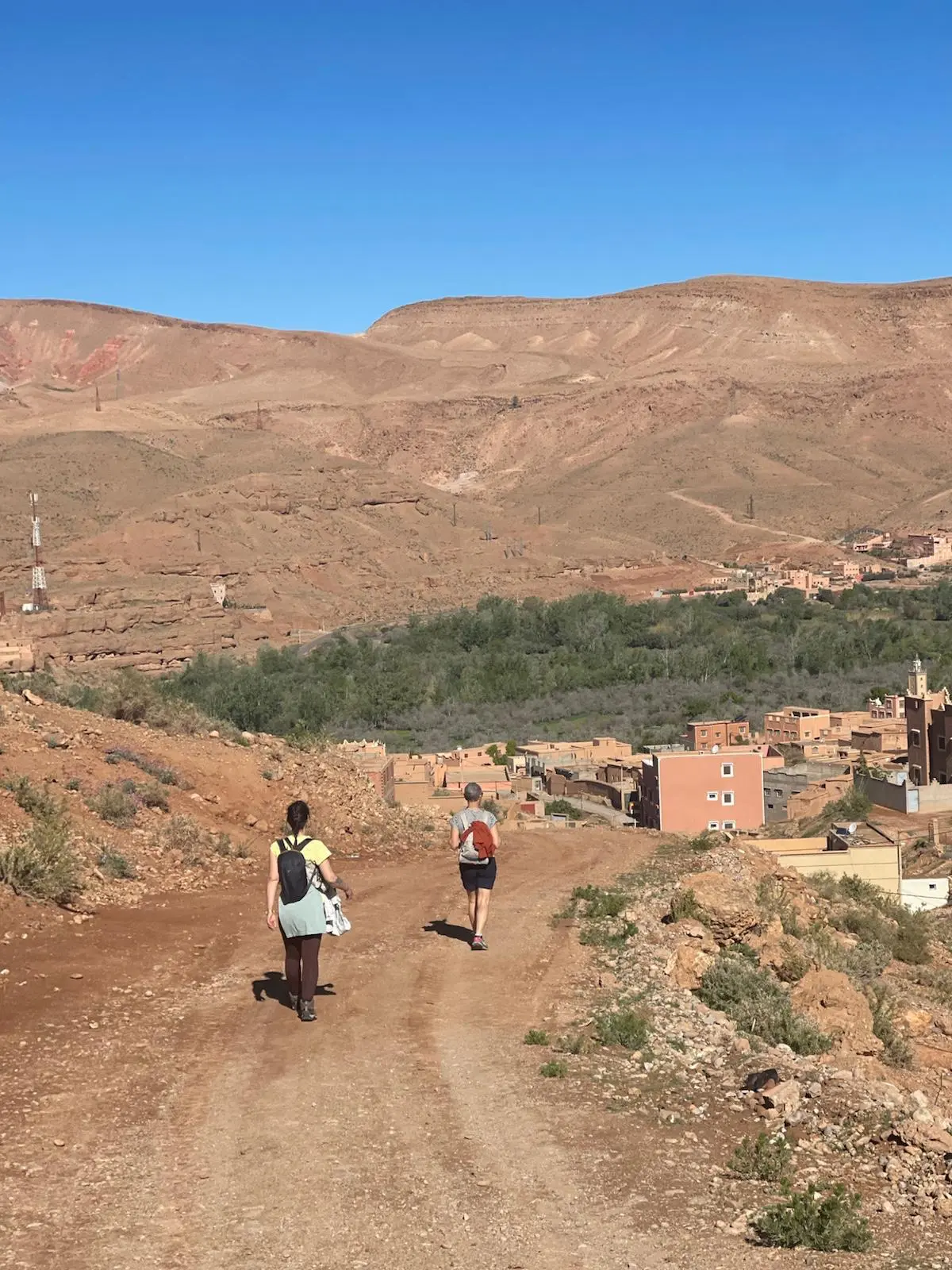 Travellers walking a path above a village and green valley